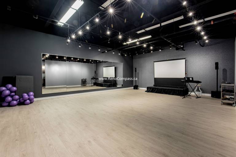 A spacious commercial studio renovation featuring luxury vinyl plank flooring, full-length mirrors, and professional track lighting. This Richmond Hill project showcases a modern industrial aesthetic with an exposed black ceiling, perfect for music schools and dance studios.