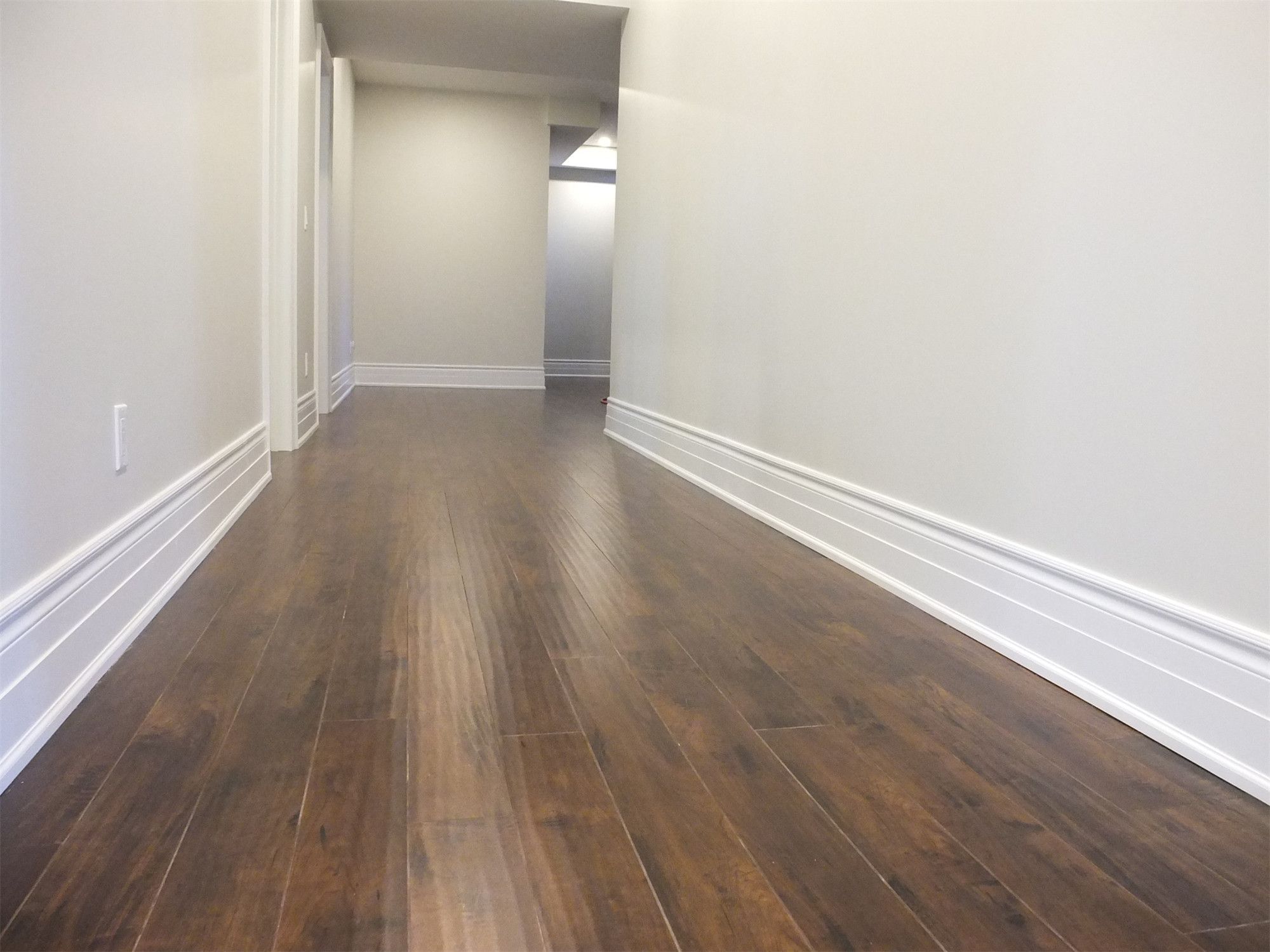 This Richmond Hill basement renovation showcases a clean and modern hallway design featuring dark hardwood flooring, smooth neutral walls, and energy-efficient recessed pot lights. The long corridor enhances flow and connectivity between basement spaces while maintaining a bright and elegant atmosphere. Professionally finished to deliver durability, comfort, and a seamless contemporary look for the home.