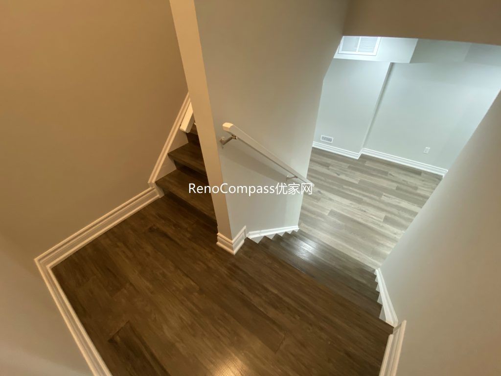 Beautifully renovated basement in Richmond Hill featuring a modern staircase with rich laminate wood flooring and soft neutral wall tones. This home renovation project by RenoCompass brings warmth and elegance to the lower level of the home.