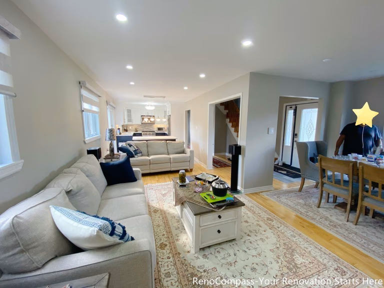 A bright open-concept living area completed as part of a Newmarket interior renovation, featuring neutral tones, recessed lighting, hardwood flooring, and a seamless connection between the living, dining, and kitchen spaces by a Toronto renovation company.
