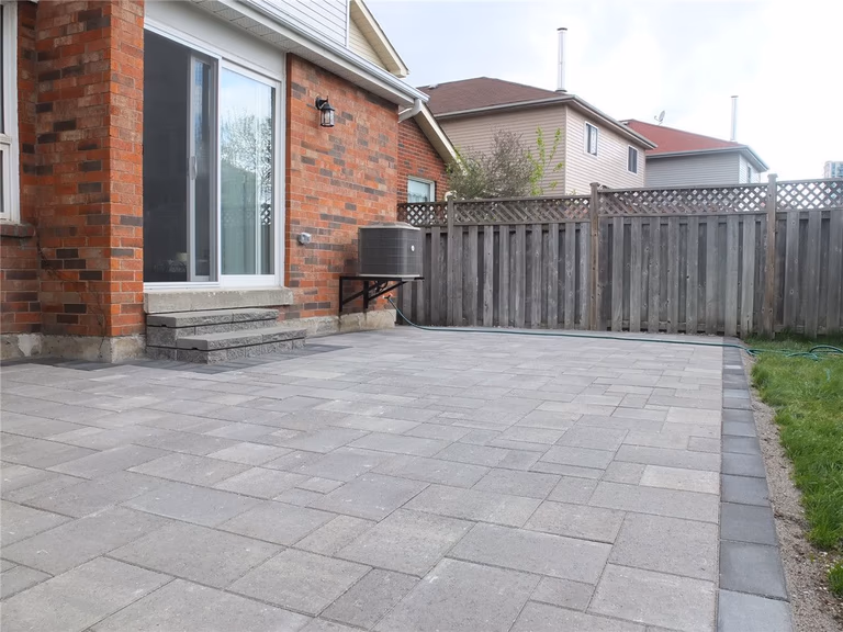 A completed backyard interlocking patio installation in Mississauga featuring large-format grey stone pavers, clean edge borders, and a modern low-maintenance outdoor design. This landscaping renovation improves outdoor usability and creates a durable patio space ideal for relaxation and gatherings. Completed by a professional Toronto Renovation Company, Reno Compass Inc., specializing in interlocking, landscaping, and exterior home upgrades across the GTA.