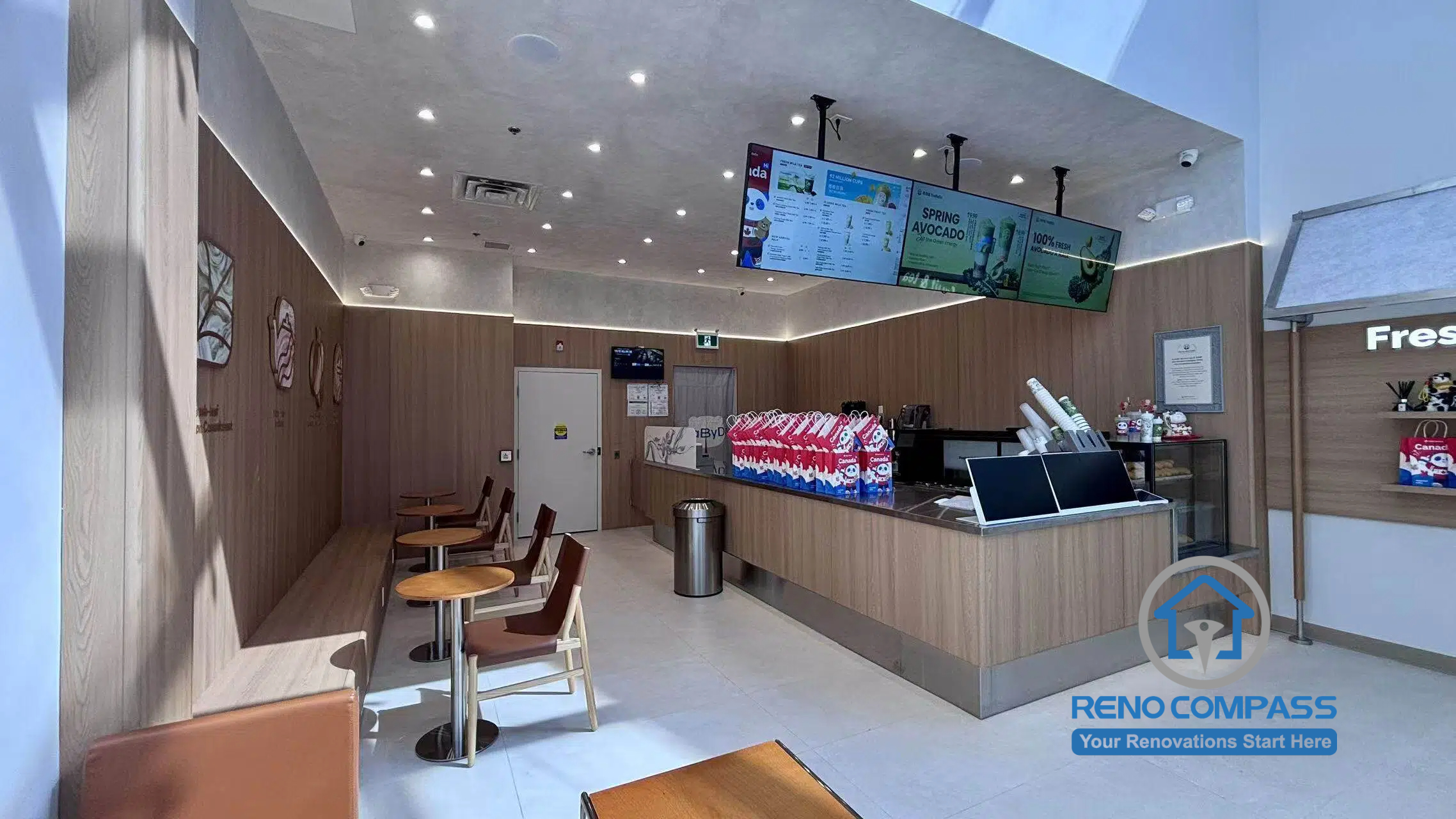 Completed TEABYDO bubble tea shop renovation in Richmond Hill featuring a modern café interior with custom beverage service counter, customer seating area, illuminated digital menu boards, warm wood-tone commercial finishes, and clean minimalist layout design. This commercial renovation project was completed by Reno Compass serving Richmond Hill, Toronto, and the GTA.