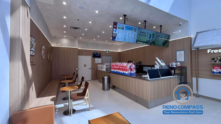 Completed TEABYDO bubble tea shop renovation in Richmond Hill featuring a modern café interior with custom beverage service counter, customer seating area, illuminated digital menu boards, warm wood-tone commercial finishes, and clean minimalist layout design. This commercial renovation project was completed by Reno Compass serving Richmond Hill, Toronto, and the GTA.