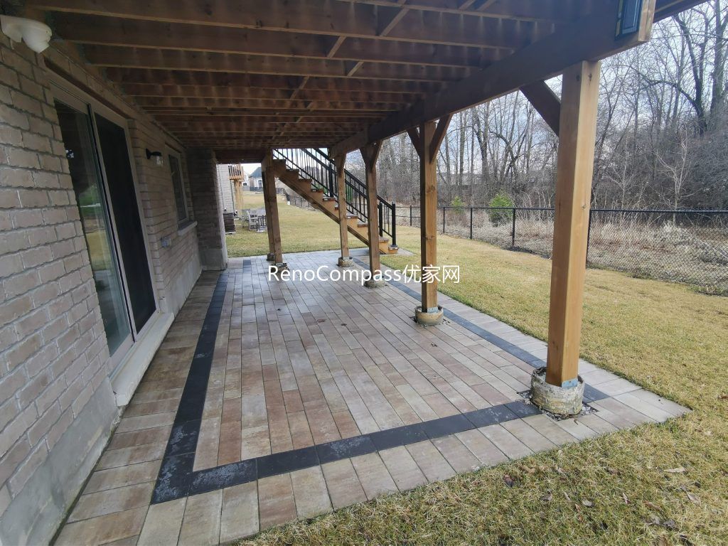 Professional interlocking patio installation in Aurora featuring durable stone pavers and clean border detailing beneath an elevated deck. This custom outdoor renovation improves drainage, usability, and backyard aesthetics while creating a functional covered patio space for all-season outdoor living.