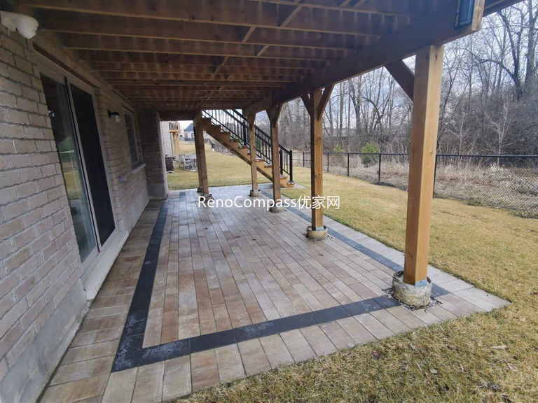 Professional interlocking patio installation in Aurora featuring durable stone pavers and clean border detailing beneath an elevated deck. This custom outdoor renovation improves drainage, usability, and backyard aesthetics while creating a functional covered patio space for all-season outdoor living.