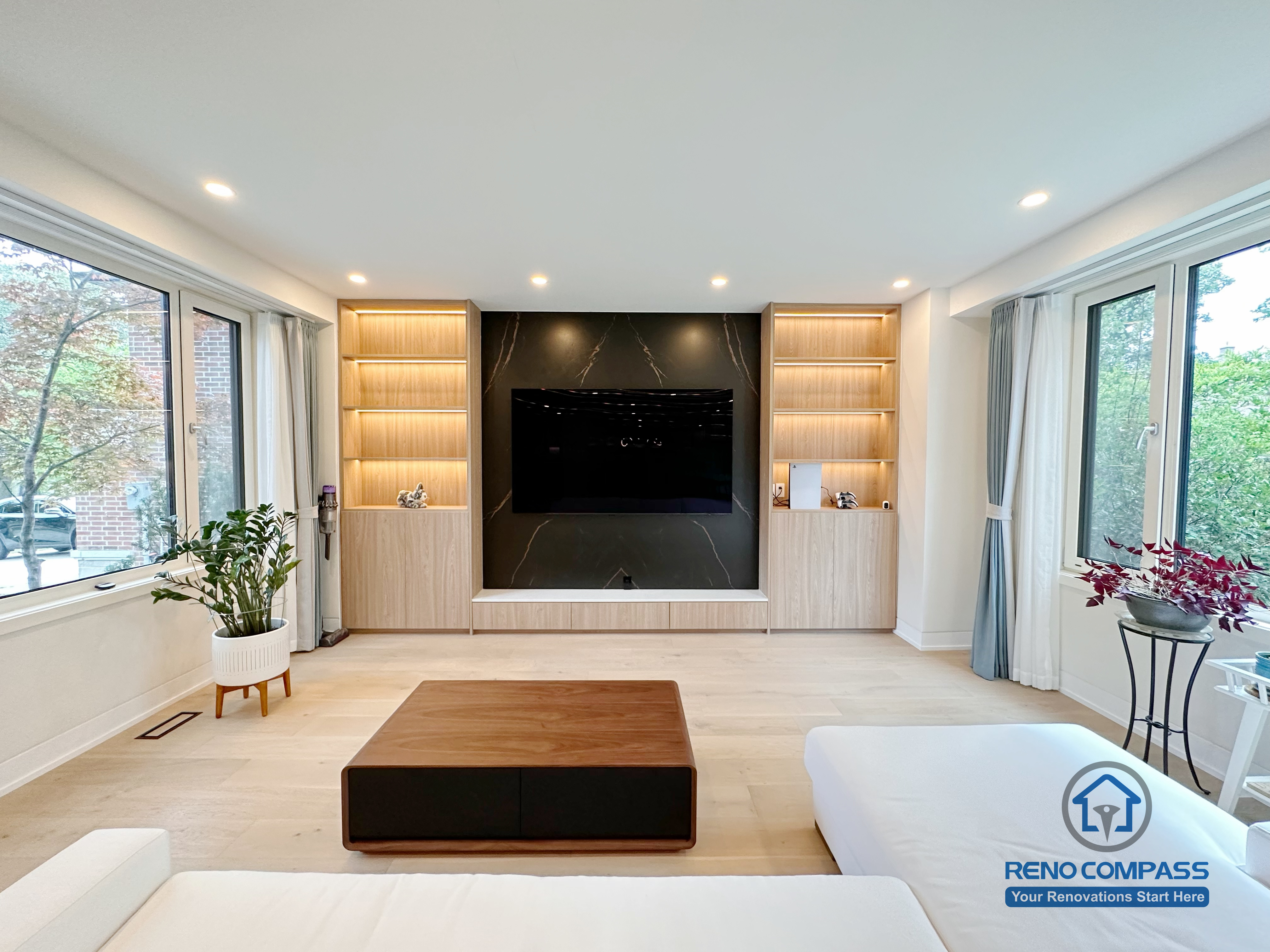 A modern living room renovation in Toronto featuring a custom media wall with built-in cabinetry and symmetrical display shelving. Integrated LED lighting and clean wood finishes create a balanced, minimalist focal point while enhancing storage and visual harmony. This whole-house custom cabinetry project was completed by a professional Toronto renovation company.