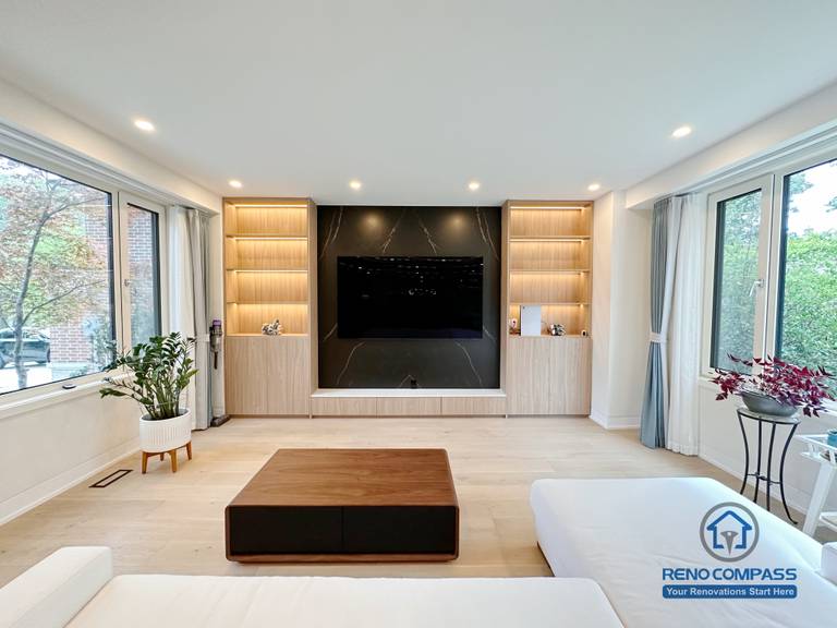 A modern living room renovation in Toronto featuring a custom media wall with built-in cabinetry and symmetrical display shelving. Integrated LED lighting and clean wood finishes create a balanced, minimalist focal point while enhancing storage and visual harmony. This whole-house custom cabinetry project was completed by a professional Toronto renovation company.