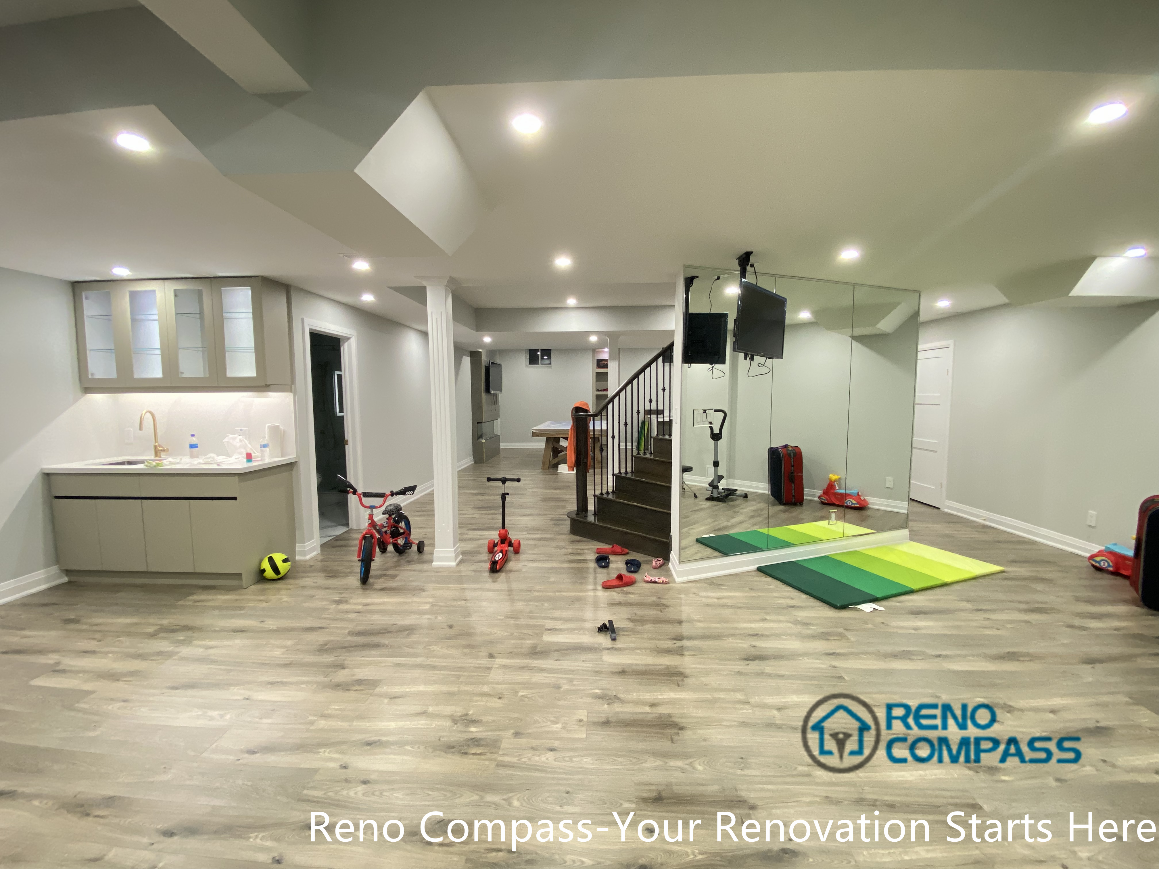 This Newmarket basement renovation showcases a spacious open-concept layout combining a family activity area, home fitness zone, custom wet bar, and seamless stair access. Designed and completed by a professional Toronto renovation company, the basement offers durable flooring, recessed lighting, and flexible zoning to support daily family use, children’s play, and multi-purpose living in a modern finished basement.