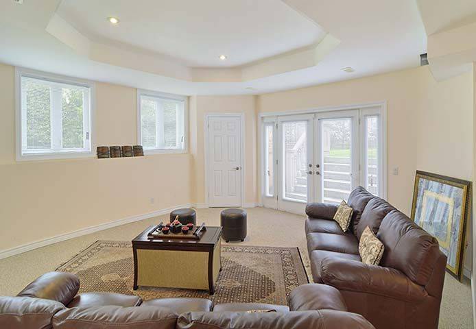 Comfortable lower level living room from a luxury Toronto home renovation featuring a bright walkout basement design, large windows, and direct access to the backyard patio. The spacious layout creates a welcoming entertainment and relaxation area with refined interior finishes. This finished basement renovation was completed by Reno Compass, a trusted Toronto Renovation Company specializing in luxury home rebuilds and interior renovations across the Greater Toronto Area.