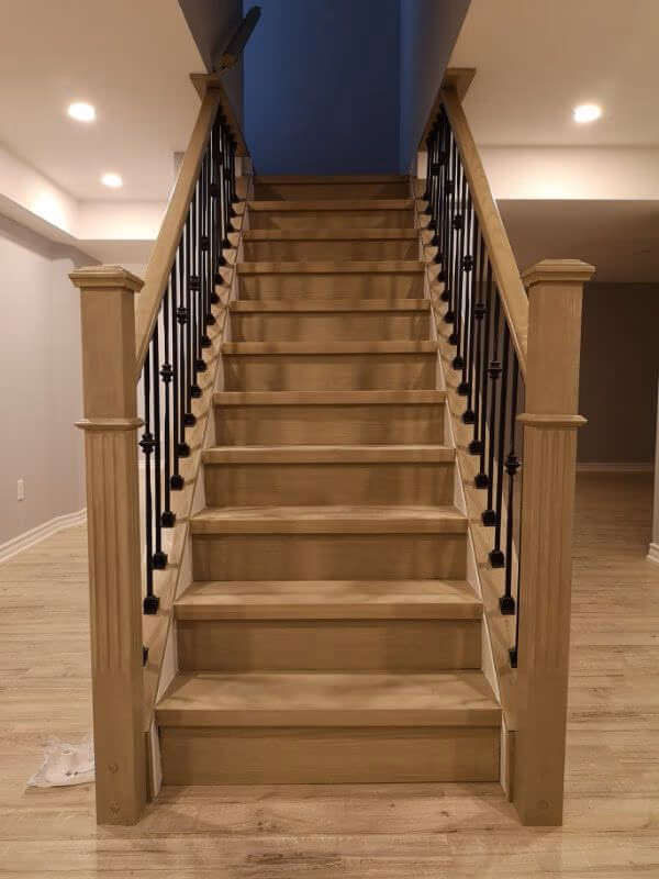 This Markham basement renovation project showcases a modern staircase upgrade with natural wood steps, black iron balusters, and newly installed light-toned flooring. Completed by a professional Toronto renovation company, the finished basement features improved layout flow, clean finishes, and a bright, comfortable living space ideal for modern family use.