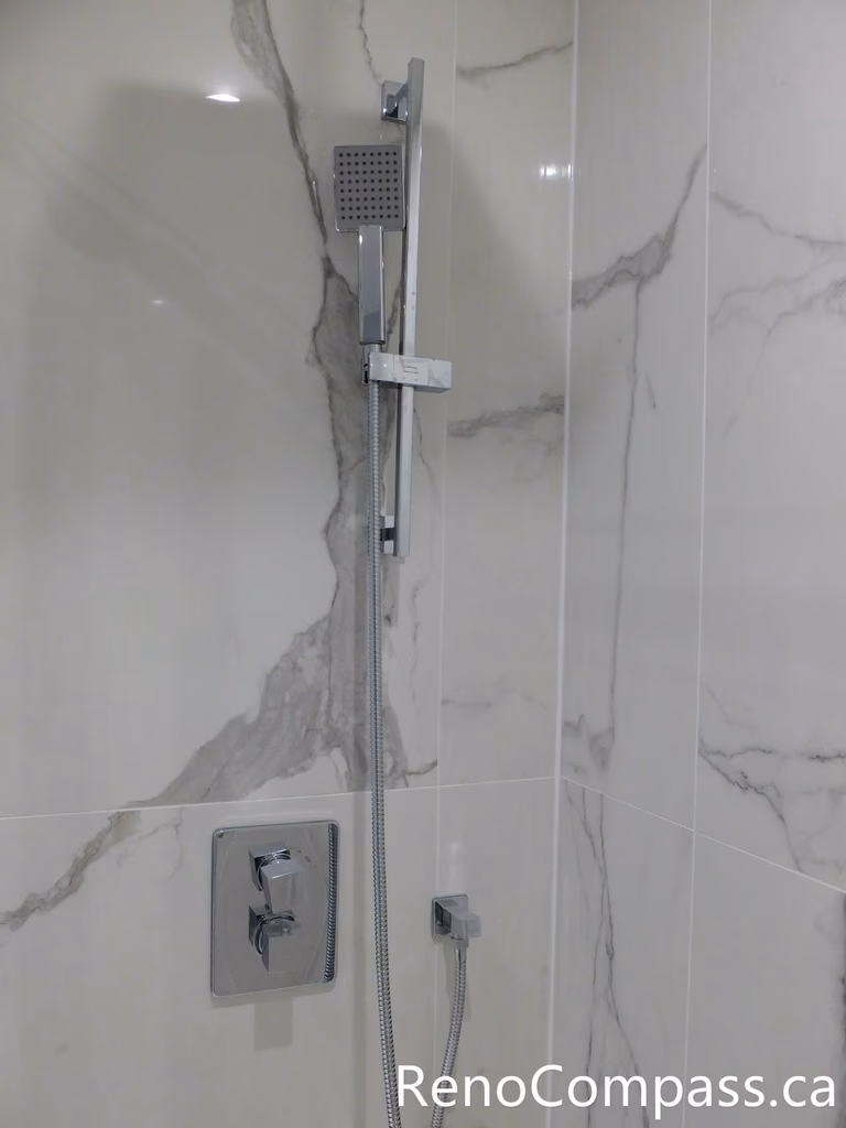 This Richmond Hill bathroom renovation features a modern shower system with a sleek handheld shower set, upgraded control valve, and marble-look porcelain wall tiles. Completed by a professional Toronto renovation company, the installation combines contemporary design, efficient water control, and durable waterproof finishes to create a comfortable and elegant shower experience.