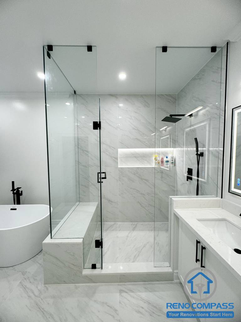 This Vaughan bathroom renovation presents a complete spa-inspired layout featuring a frameless glass shower, freestanding bathtub, and custom double vanity with quartz countertops. Large-format marble-look tiles, matte black fixtures, and integrated lighting create a bright, cohesive, and modern atmosphere. Completed by an experienced Toronto Renovation Company, this bathroom design emphasizes comfort, functionality, and clean contemporary craftsmanship.