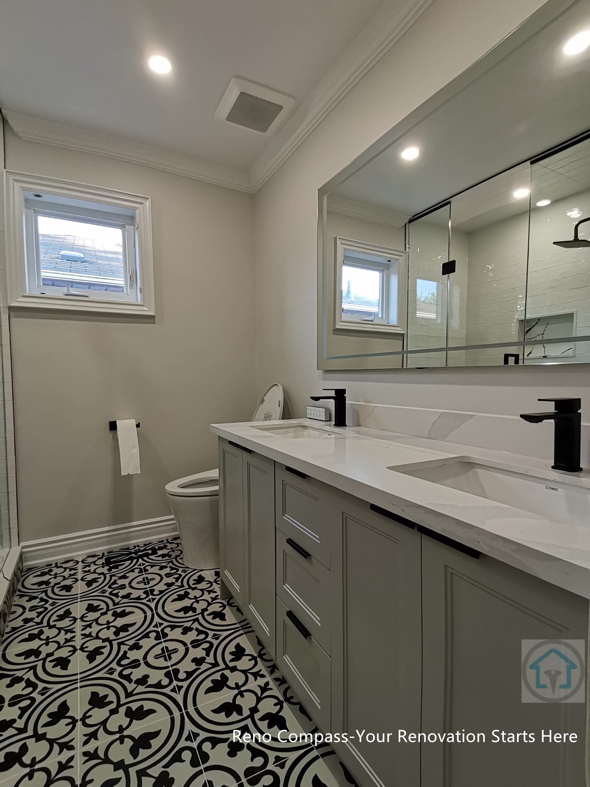 This Thornhill bathroom renovation showcases a clean and well-balanced layout featuring a double vanity, modern black fixtures, and a large wall-mounted mirror. Patterned floor tiles add visual interest, while neutral finishes and recessed lighting create a bright, functional bathroom designed for everyday use.