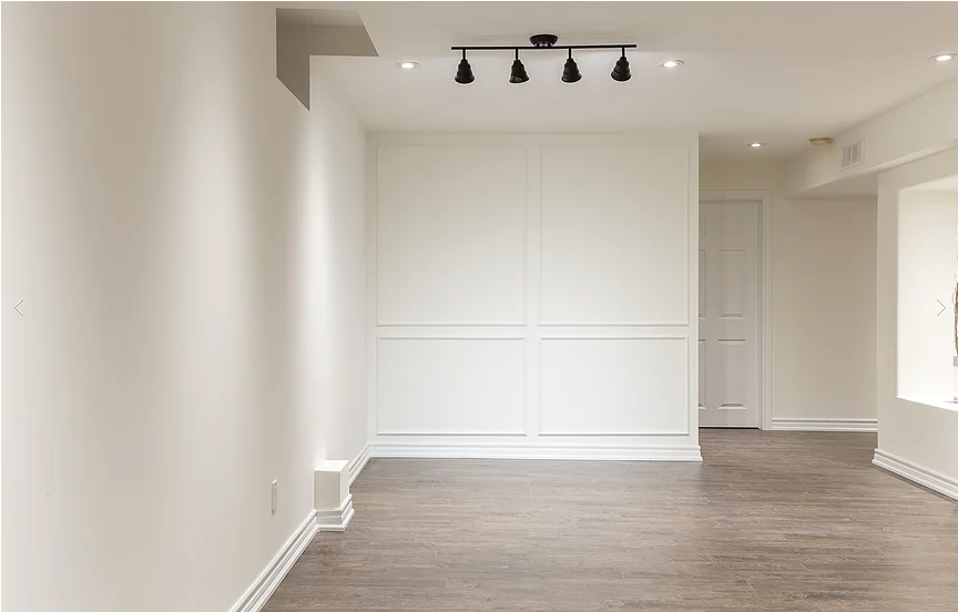 A beautifully finished basement from our Vaughan full house interior renovation, featuring light neutral walls, wood-look flooring, and modern recessed lighting. The open layout and clean trim details create a welcoming, multifunctional living space for family use or entertainment.