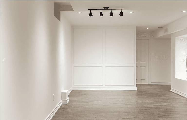 A beautifully finished basement from our Vaughan full house interior renovation, featuring light neutral walls, wood-look flooring, and modern recessed lighting. The open layout and clean trim details create a welcoming, multifunctional living space for family use or entertainment.