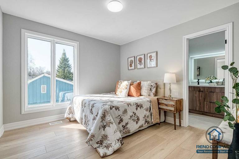 This Georgian interior renovation features a bright primary bedroom with large windows, light wood flooring, and direct access to an ensuite bathroom. The calm layout and cohesive finishes reflect the quality craftsmanship of a Toronto renovation company.