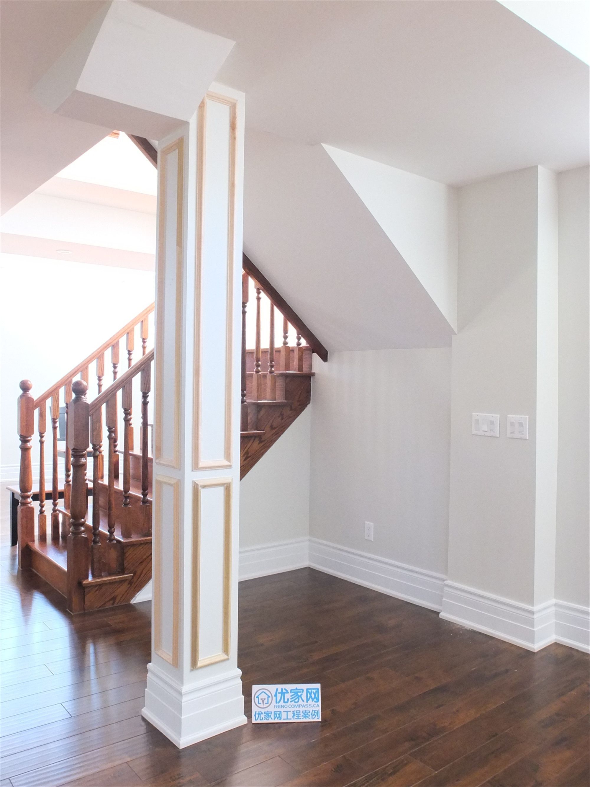 This Richmond Hill basement renovation features a spacious open-concept layout with dark hardwood flooring, modern pot lights, and structural columns with decorative trim. The upgraded staircase design adds warmth and elegance, making the basement ideal for a family living area or entertainment space.