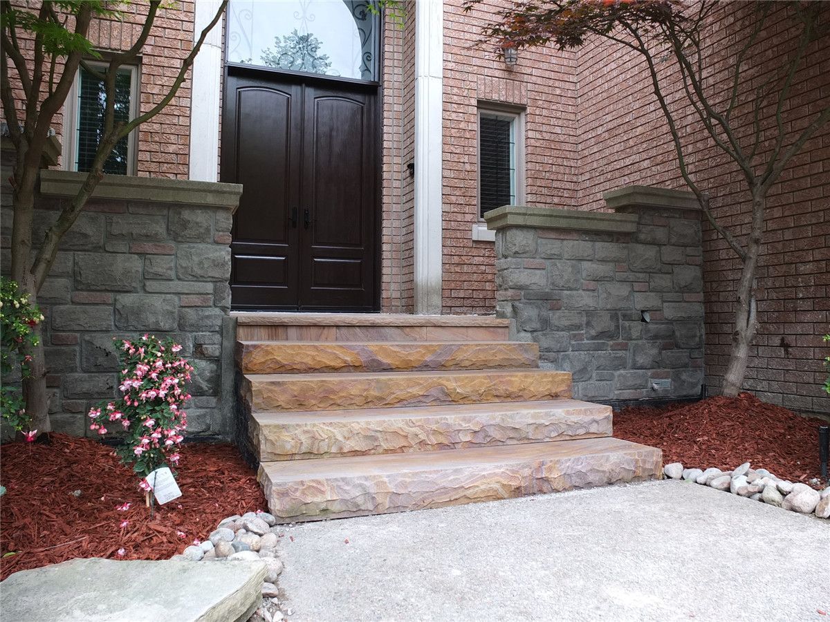 This Richmond Hill front yard landscaping renovation features a beautifully upgraded entrance with custom natural stone steps, decorative interlock detailing, and refined garden landscaping. The project enhances curb appeal with professionally installed stone stair treads, structured side walls, and fresh mulch planting beds that frame the main entrance. Designed for both durability and visual impact, the upgraded front entry creates a welcoming and elegant transition to the home while improving accessibility and long-term exterior value. Completed with precision and quality craftsmanship, this project highlights modern front yard landscaping and entrance design.
