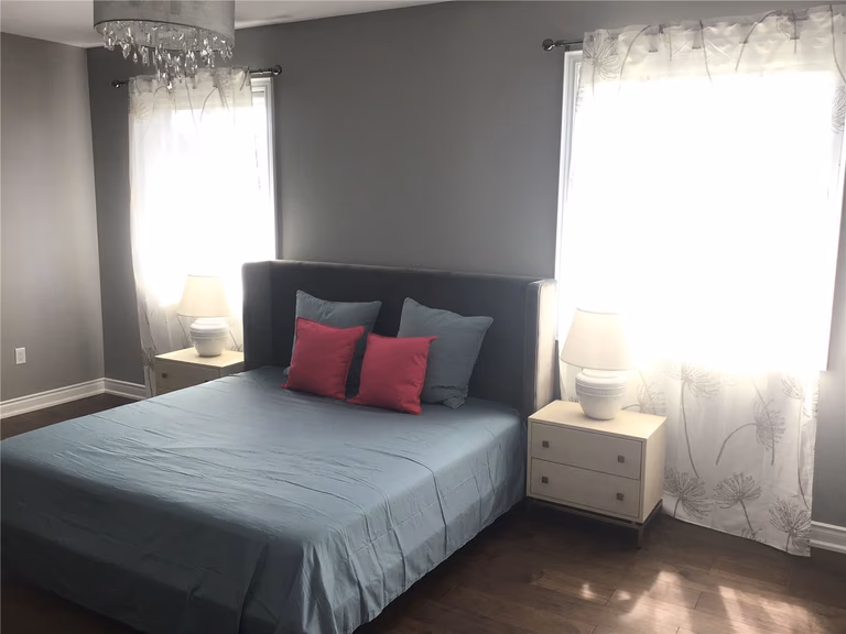 This Markham full home renovation features a cozy and modern bedroom with rich hardwood flooring, large windows, and soft neutral tones. The space is enhanced by natural light, elegant lighting fixtures, and a clean layout that creates a comfortable and relaxing atmosphere. Completed by a trusted Toronto Renovation Company, this bedroom design reflects both simplicity and everyday livability.