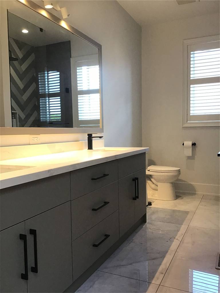 This Markham full home renovation features a sleek and contemporary bathroom with a custom grey vanity, integrated LED mirror lighting, and polished tile flooring. The clean layout, matte black fixtures, and soft ambient lighting create a refined and functional space. Completed by a professional Toronto Renovation Company, this bathroom design combines modern aesthetics with everyday practicality.
