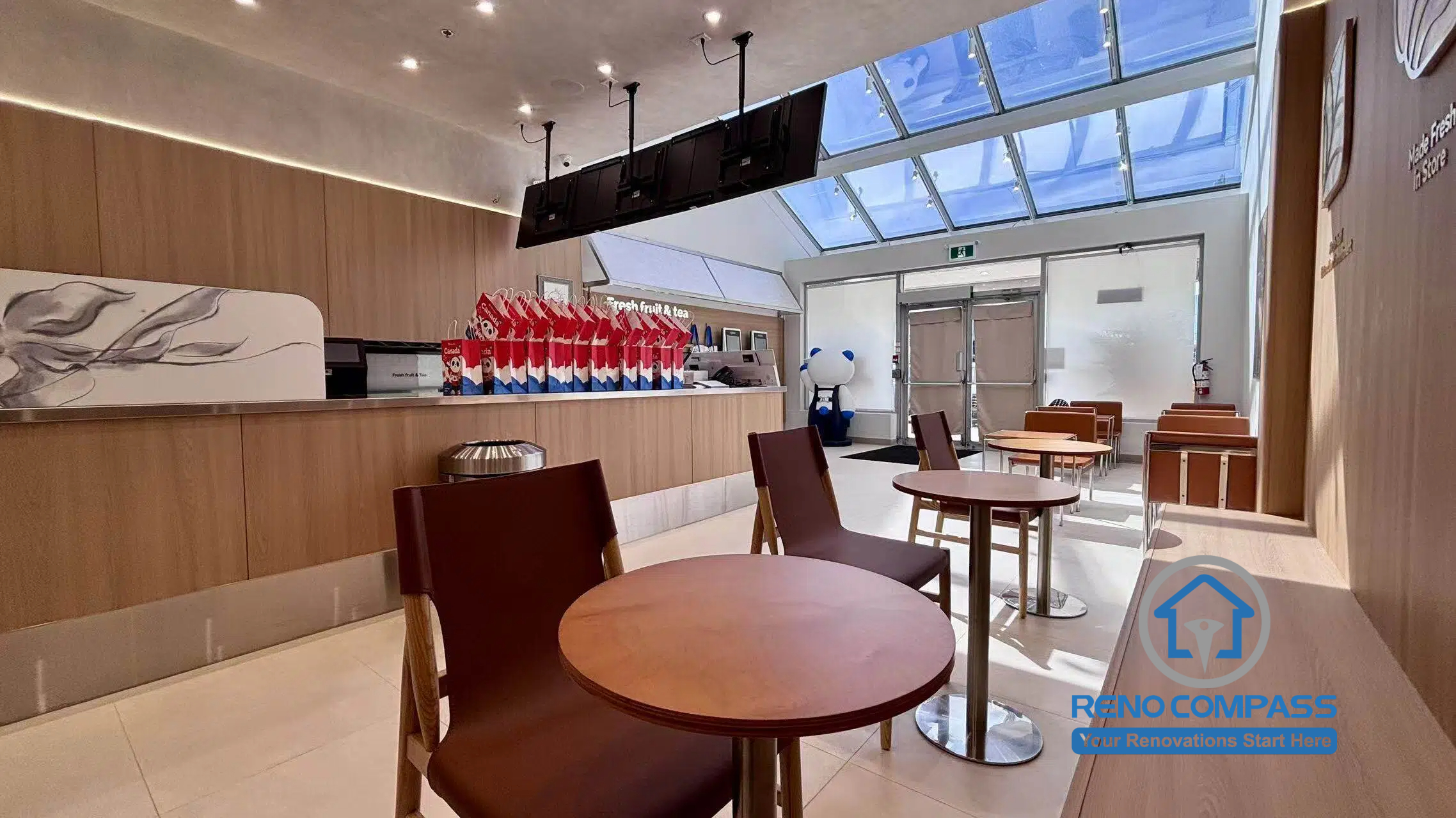 Completed TEABYDO bubble tea shop renovation in Richmond Hill featuring modern customer seating, custom beverage service counter, skylight ceiling, warm wood-tone commercial finishes, integrated LED lighting, and clean minimalist café interior design. This bright and welcoming commercial renovation project was completed by Reno Compass serving Richmond Hill, Toronto, and the GTA.