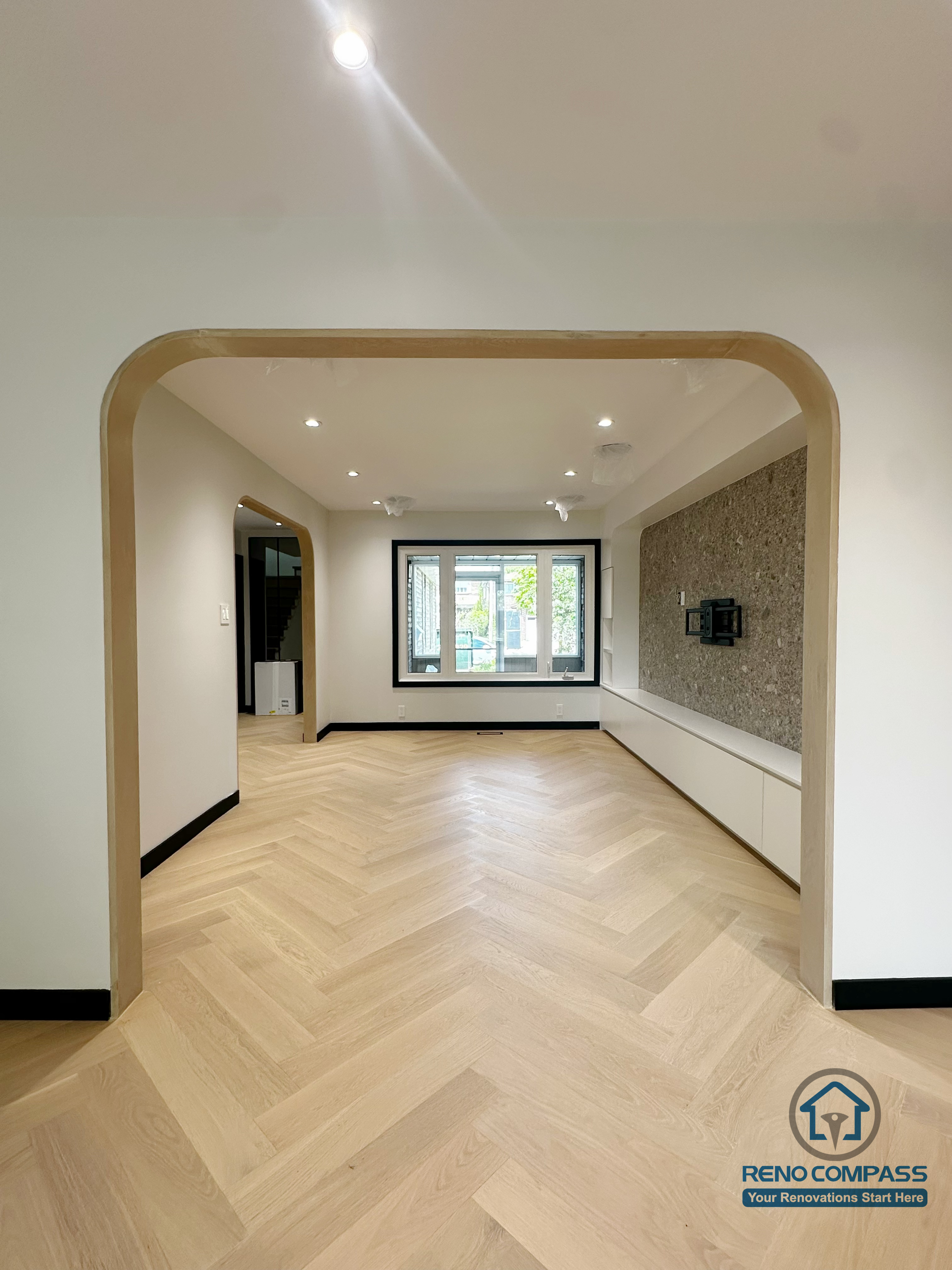 A beautifully designed open-concept living area featuring a soft-curve archway, light herringbone flooring, and a minimalist TV feature wall.
The warm tones and seamless flow between rooms create an inviting, modern, and airy atmosphere throughout the home. 一个以柔和弧形拱门为亮点的开放式客厅空间，搭配浅色人字拼地板与极简电视背景墙。
整体色调温暖、动线连贯，营造出现代、通透又舒适的居家氛围。