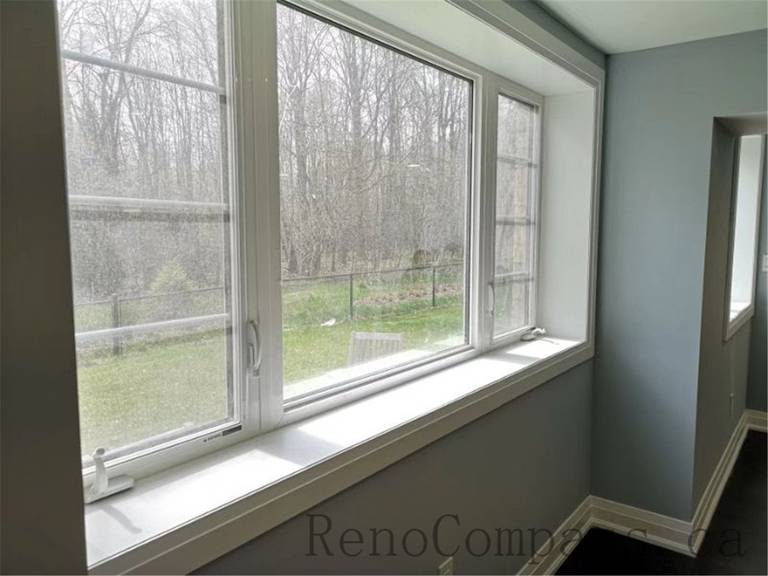 This cozy basement lounge in Aurora features elegant wall finishes, large windows, and modern flooring. The space is designed to bring warmth and openness, beautifully finished by Reno Compass.