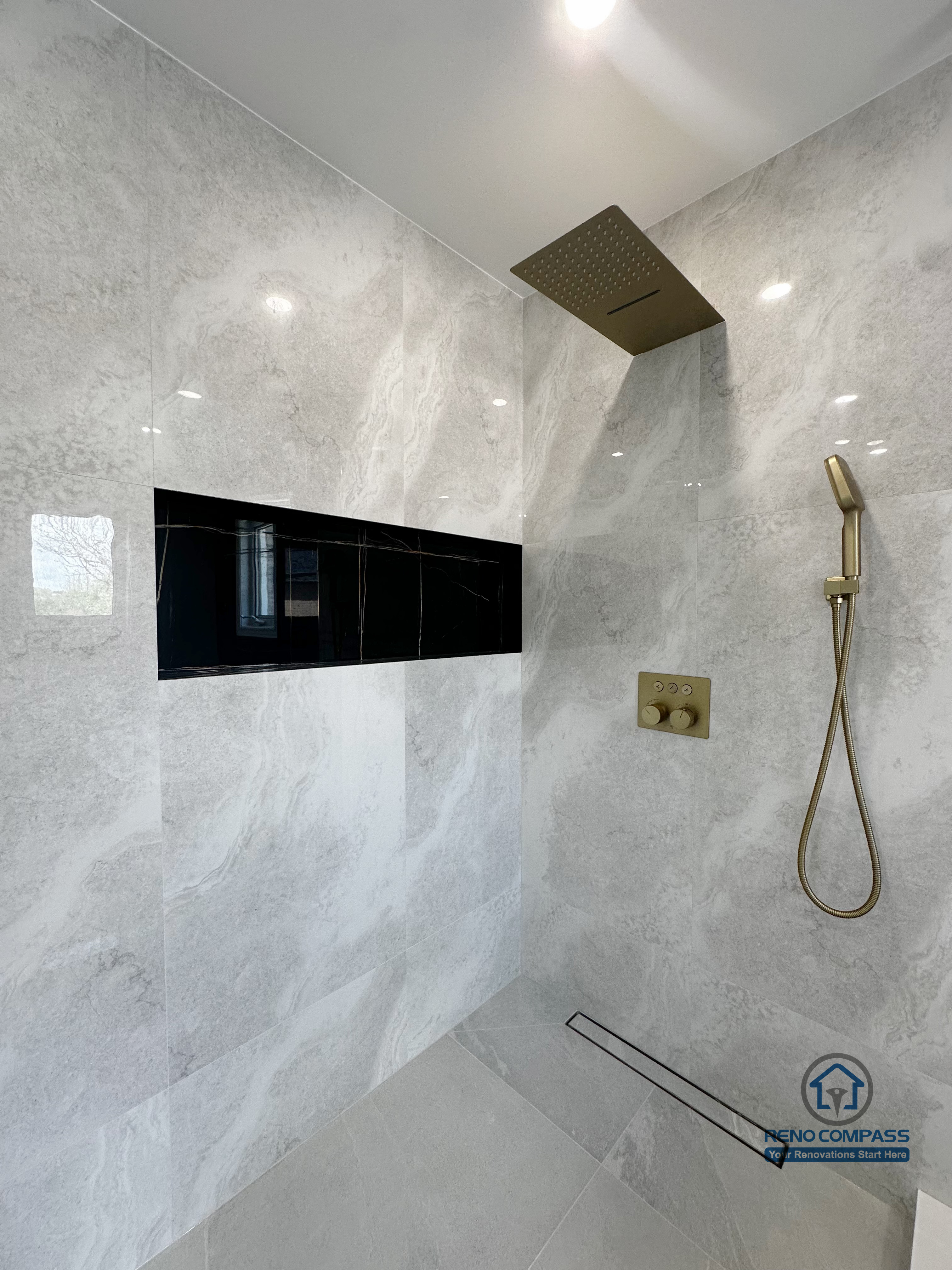 This image features a walk-in shower from a Markham interior renovation project, designed with a clean, modern aesthetic and a strong focus on functionality. Large-format stone-look wall tiles create a seamless, continuous surface, enhancing the sense of space while minimizing visual clutter.