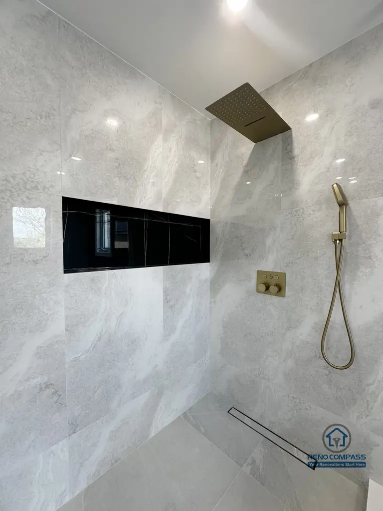 This image features a walk-in shower from a Markham interior renovation project, designed with a clean, modern aesthetic and a strong focus on functionality. Large-format stone-look wall tiles create a seamless, continuous surface, enhancing the sense of space while minimizing visual clutter.