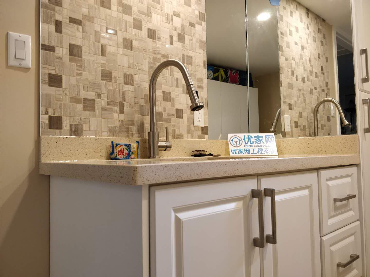 Close-up view of a custom basement wet bar completed during a Scarborough interior renovation project. The space features a quartz countertop, stainless steel pull-down faucet, decorative mosaic tile backsplash, and modern white cabinetry, creating a clean and functional bar area for everyday use and entertaining.