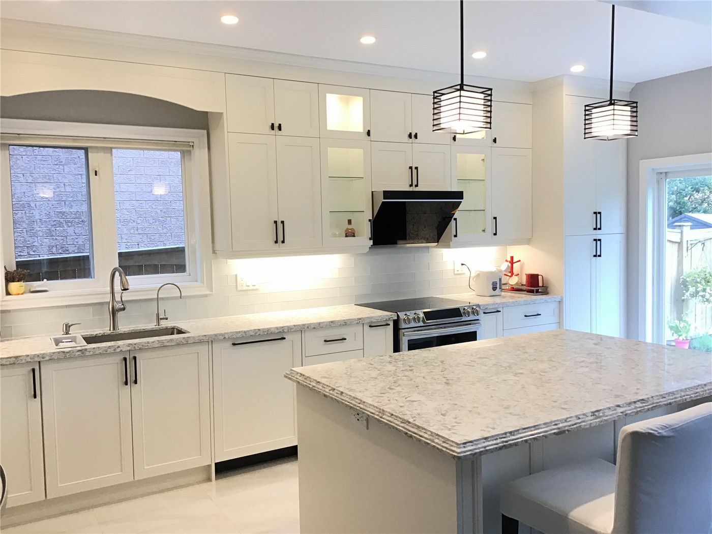 This Richmond Hill interior renovation features a bright and modern white kitchen design with full-height custom cabinetry, a large quartz island, and sleek black hardware accents. The space is enhanced by under-cabinet lighting, stainless steel appliances, and a functional layout that maximizes storage and usability. Completed by a professional Toronto renovation company, this project combines elegance, practicality, and timeless appeal.