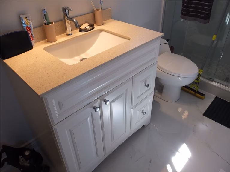 This Richmond Hill bathroom renovation features a clean white vanity with quartz countertop, modern undermount sink, upgraded faucet, and sleek glass shower enclosure. The bright flooring and functional layout enhance daily comfort and property value, showcasing professional craftsmanship by a trusted Toronto renovation company serving Richmond Hill and the GTA.