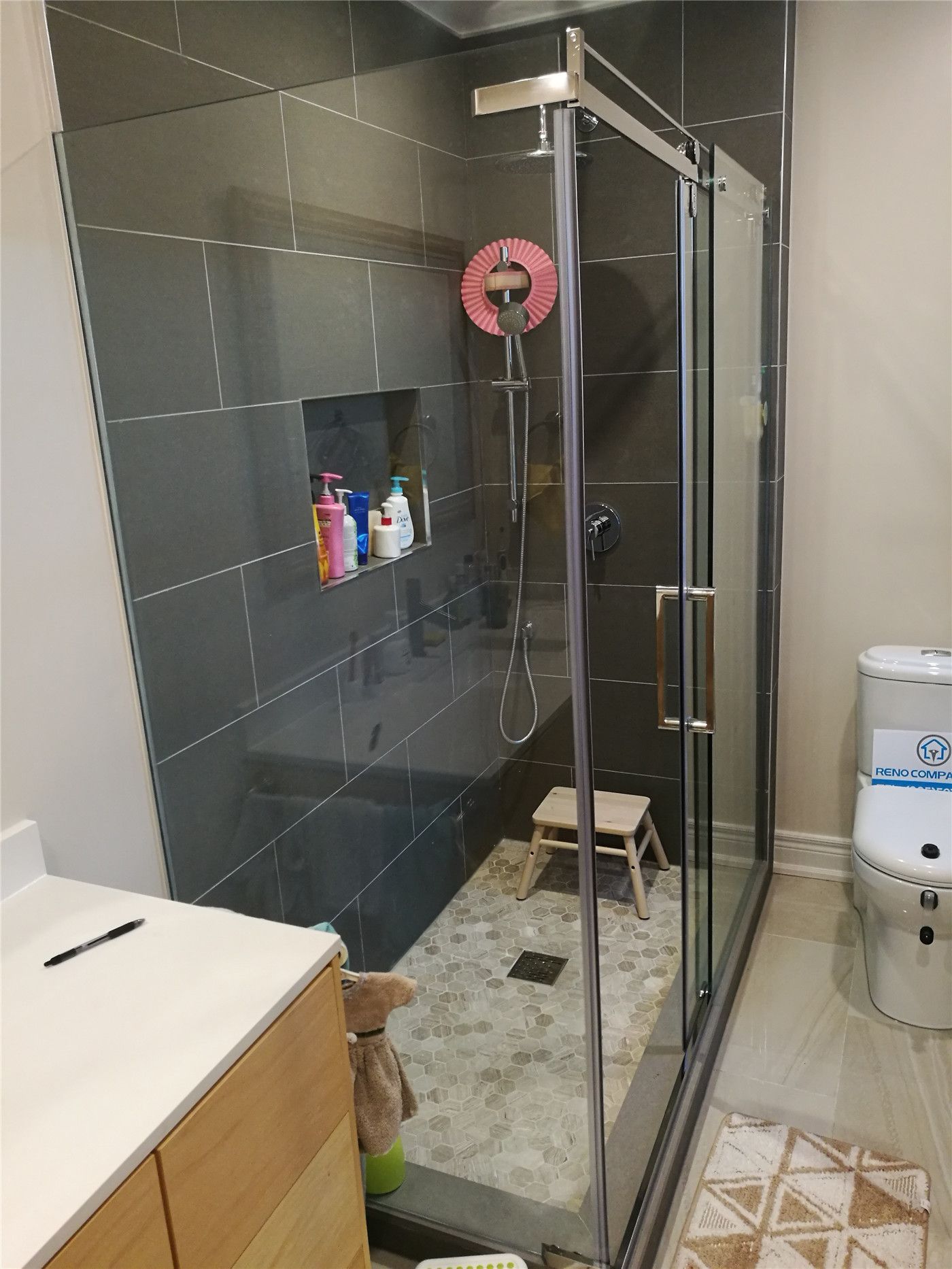 This Richmond Hill bathroom renovation features a sleek glass shower enclosure with dark large-format wall tiles, a built-in shower niche, and modern matte fixtures. The bathroom design combines durability and style with a contemporary vanity, upgraded flooring, and efficient layout to maximize comfort and functionality. Completed by a trusted Toronto renovation company, this project highlights professional bathroom renovation craftsmanship and modern design solutions for homeowners in Richmond Hill and throughout the GTA.