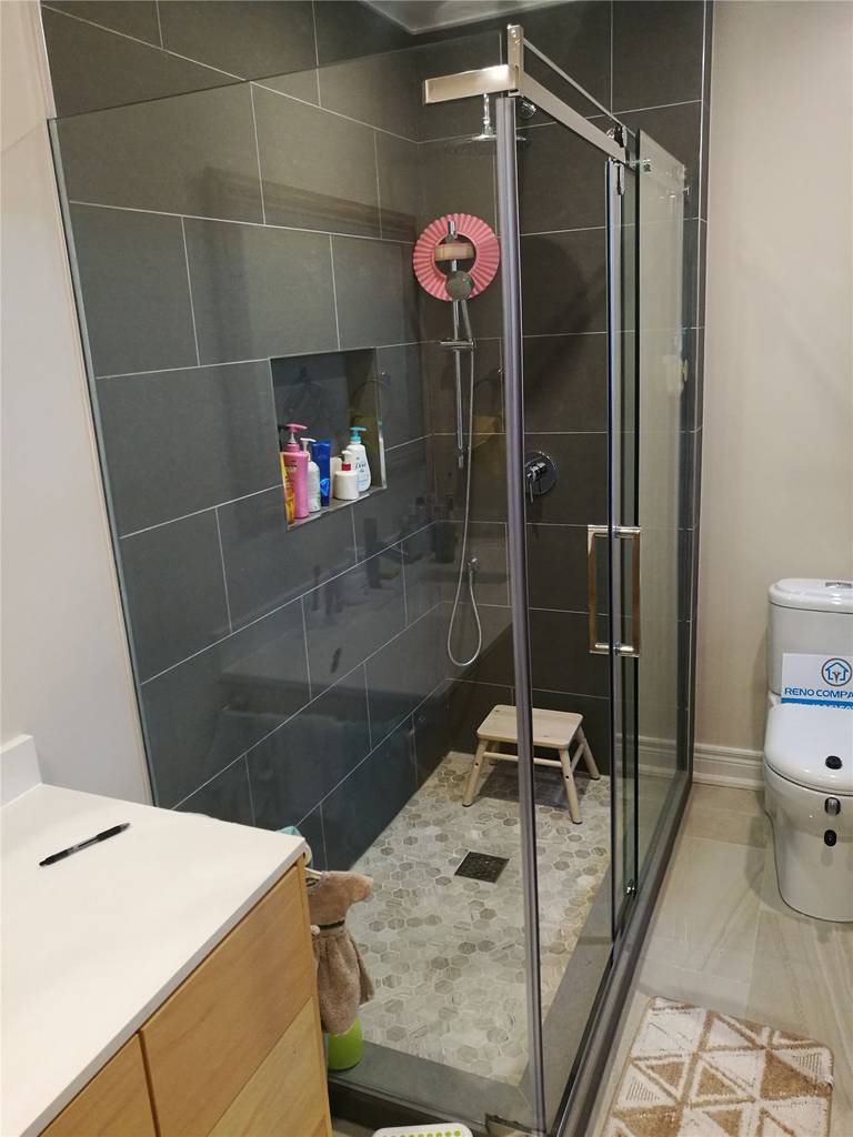 This Richmond Hill bathroom renovation features a sleek glass shower enclosure with dark large-format wall tiles, a built-in shower niche, and modern matte fixtures. The bathroom design combines durability and style with a contemporary vanity, upgraded flooring, and efficient layout to maximize comfort and functionality. Completed by a trusted Toronto renovation company, this project highlights professional bathroom renovation craftsmanship and modern design solutions for homeowners in Richmond Hill and throughout the GTA.