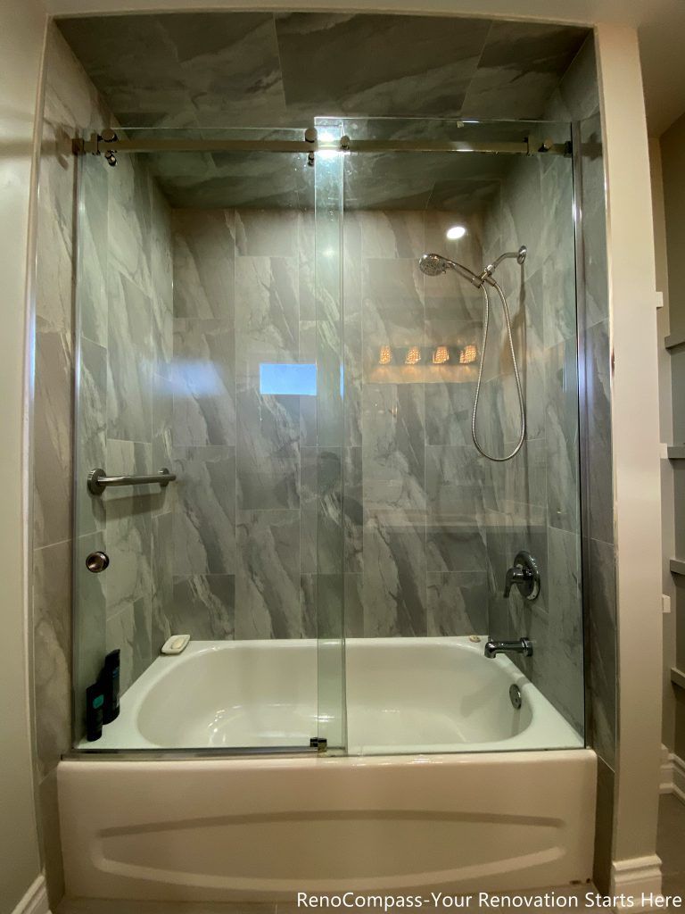 This Mississauga bathroom renovation features a combined bathtub and shower enclosure with full-height marble-look wall tiles and a clear glass sliding door. The design improves water containment and visual openness while keeping the layout practical for everyday use. Neutral tones and clean tile lines help the space feel brighter and more refined.
City: Mississauga · Toronto contractor: Reno Compass
