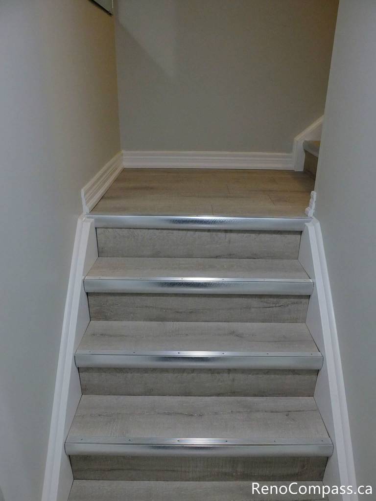 Upgraded basement staircase in Markham featuring durable laminate stair treads, clean white risers, and integrated LED step lighting for enhanced safety and modern appeal. The neutral tones seamlessly connect the basement to the main floor, creating a cohesive design. Completed by a trusted Toronto renovation company, this project highlights attention to detail and quality finishing craftsmanship.