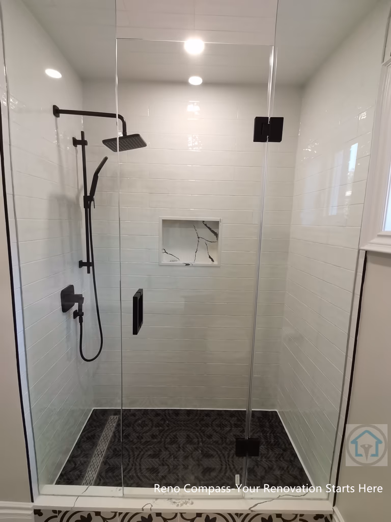 This Thornhill bathroom renovation features a glass-enclosed shower with modern black fixtures, a built-in niche, and clean subway-style wall tiles. The frameless design improves light flow and visual openness, while patterned floor tiles add contrast and character to the shower area.