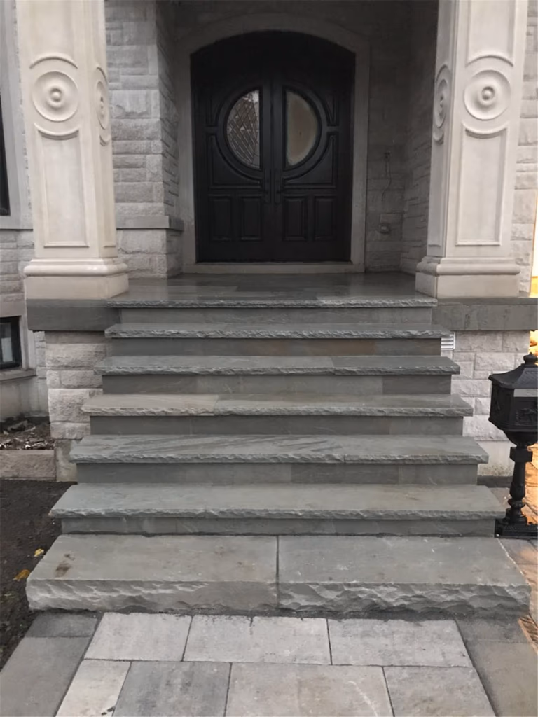 Front entrance landscaping renovation in Toronto featuring custom natural stone steps, interlocking walkway, and elegant entry design that enhances curb appeal and provides a durable, functional access to the home.
