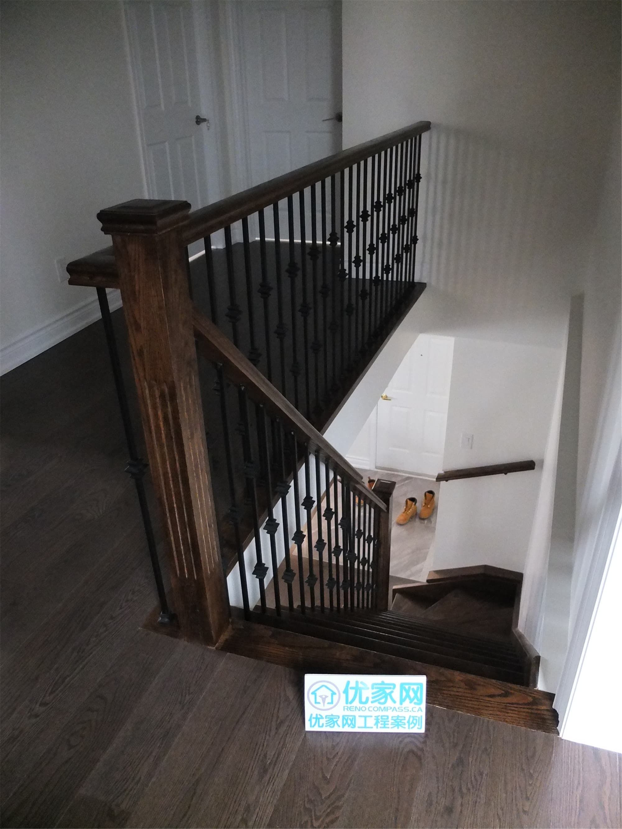 Custom staircase renovation in a Scarborough home addition project featuring dark hardwood flooring, solid wood posts, and decorative wrought iron railings. The upgraded staircase enhances both safety and architectural style, creating a modern transition between floors as part of the full interior renovation.