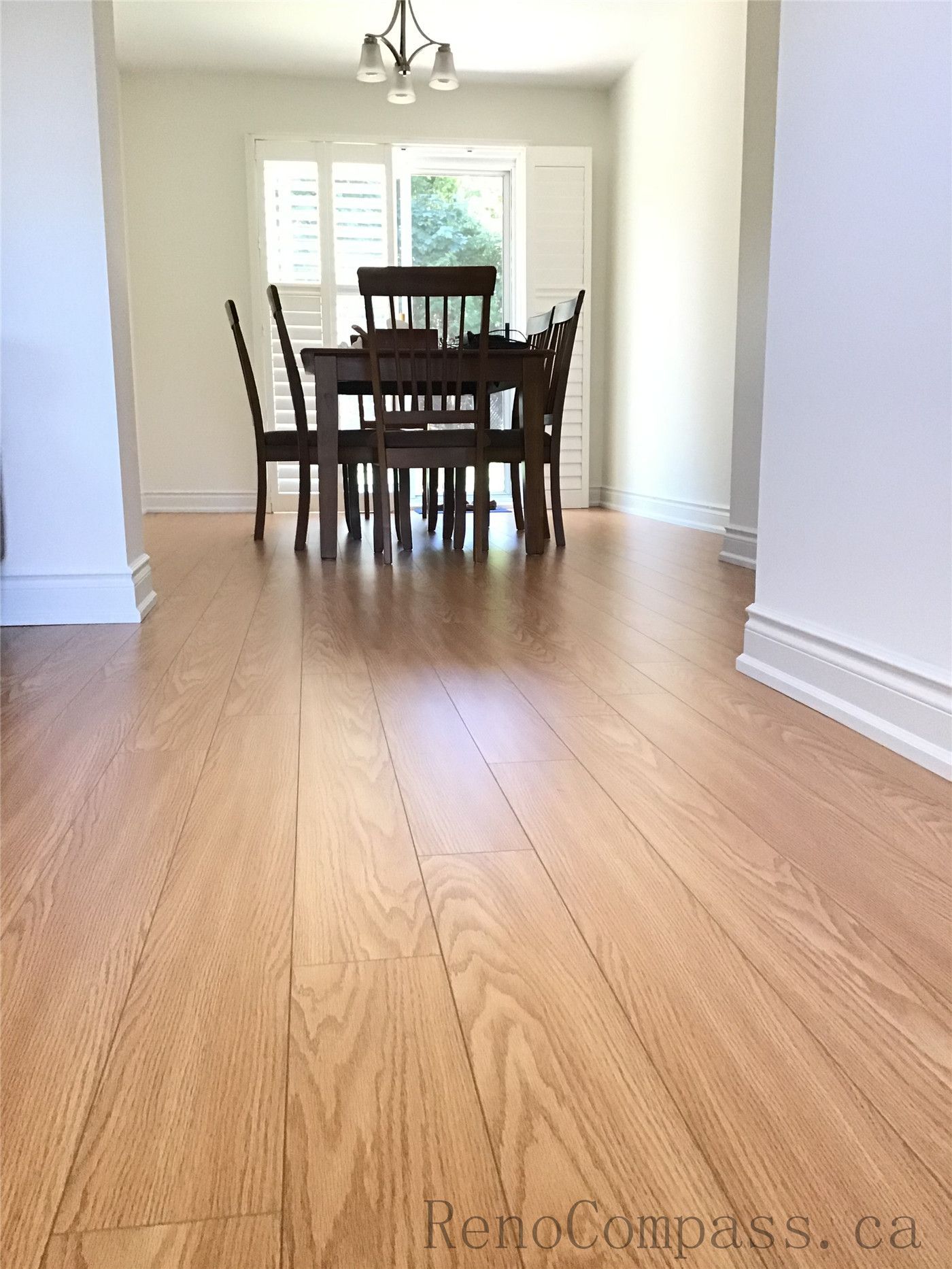 This image highlights an open-concept interior flooring renovation in Oakville, where newly installed hardwood flooring extends seamlessly into the dining area. The natural wood texture and linear layout enhance visual depth, while the clean white walls and natural light create a bright, spacious, and modern atmosphere.