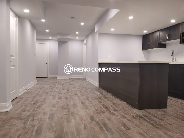 This Markham basement renovation showcases a fully finished open-concept basement featuring waterproof vinyl flooring, recessed pot lighting, and a custom bar and kitchenette area. The modern layout provides a spacious and functional environment ideal for family living, entertainment, or rental potential. Neutral wall tones and clean finishing details enhance brightness and create a comfortable atmosphere throughout the space. Completed by a professional Toronto renovation company, this project highlights quality craftsmanship, practical basement design, and durable materials tailored for modern homes in the Greater Toronto Area.
