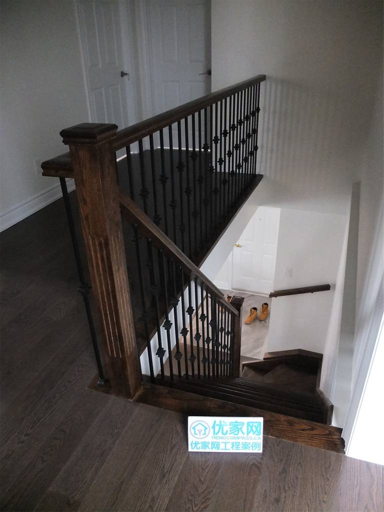 Custom staircase renovation in a Scarborough home addition project featuring dark hardwood flooring, solid wood posts, and decorative wrought iron railings. The upgraded staircase enhances both safety and architectural style, creating a modern transition between floors as part of the full interior renovation.