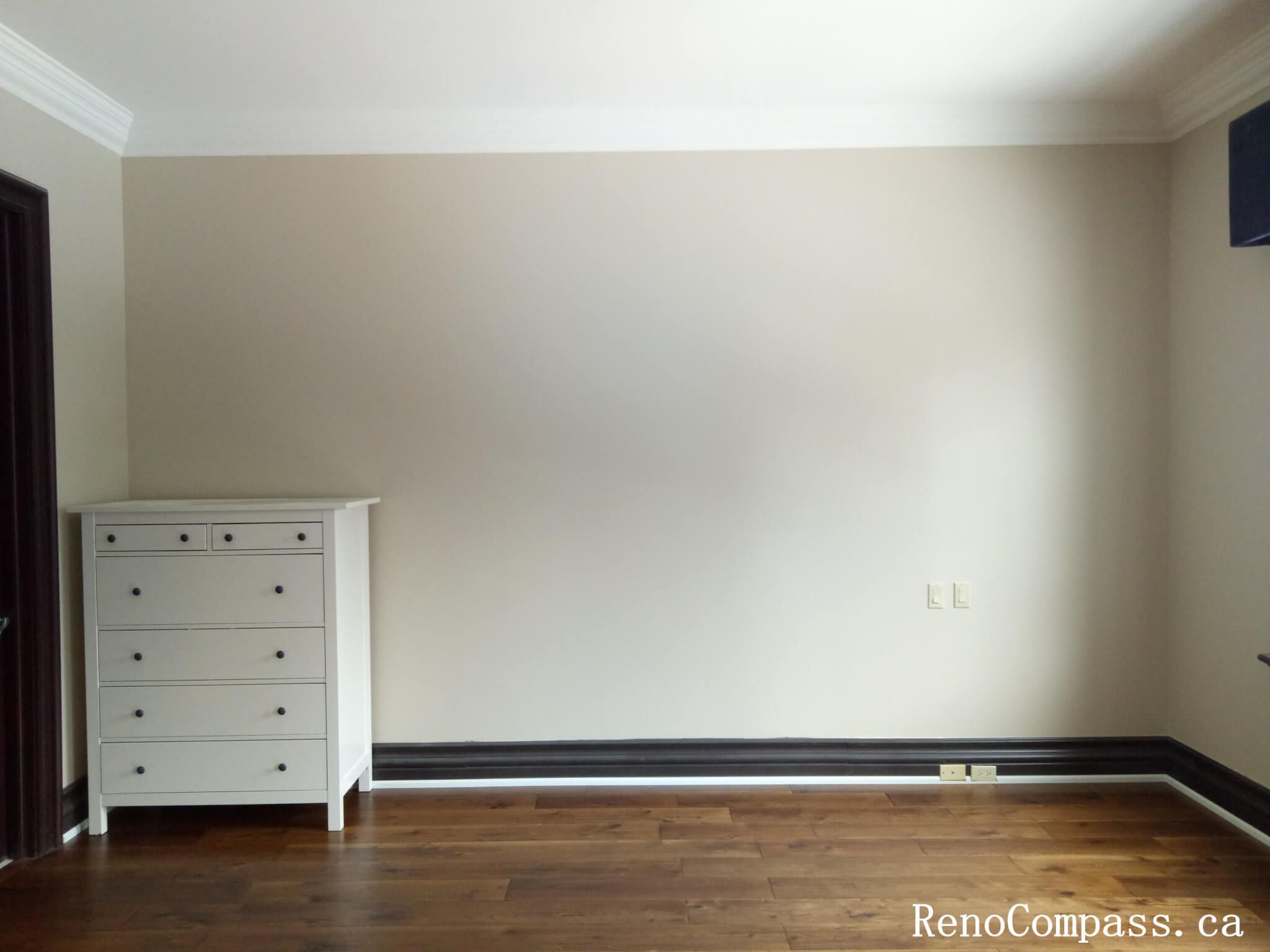 This image features a clean and professionally finished interior painting project in North York, highlighting smooth neutral-toned walls paired with classic crown molding and baseboards. The freshly painted surface enhances natural light and creates a calm, balanced atmosphere that complements the hardwood flooring. Careful edge detailing around ceilings, trim, and electrical outlets reflects high-quality workmanship and precise execution. This North York painting project demonstrates a timeless interior finish suitable for bedrooms, living spaces, or home offices, delivering a polished and well-maintained look.