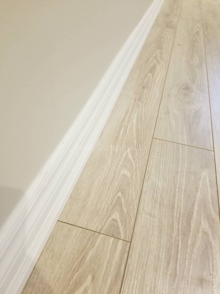 This Toronto basement renovation showcases newly installed light wood flooring paired with clean white baseboards for a modern and elegant finish. The durable laminate flooring enhances brightness and creates a warm, contemporary look while providing easy maintenance for basement living spaces. Installed by Reno Compass Inc., this flooring upgrade adds both style and functionality to the newly renovated basement interior.
