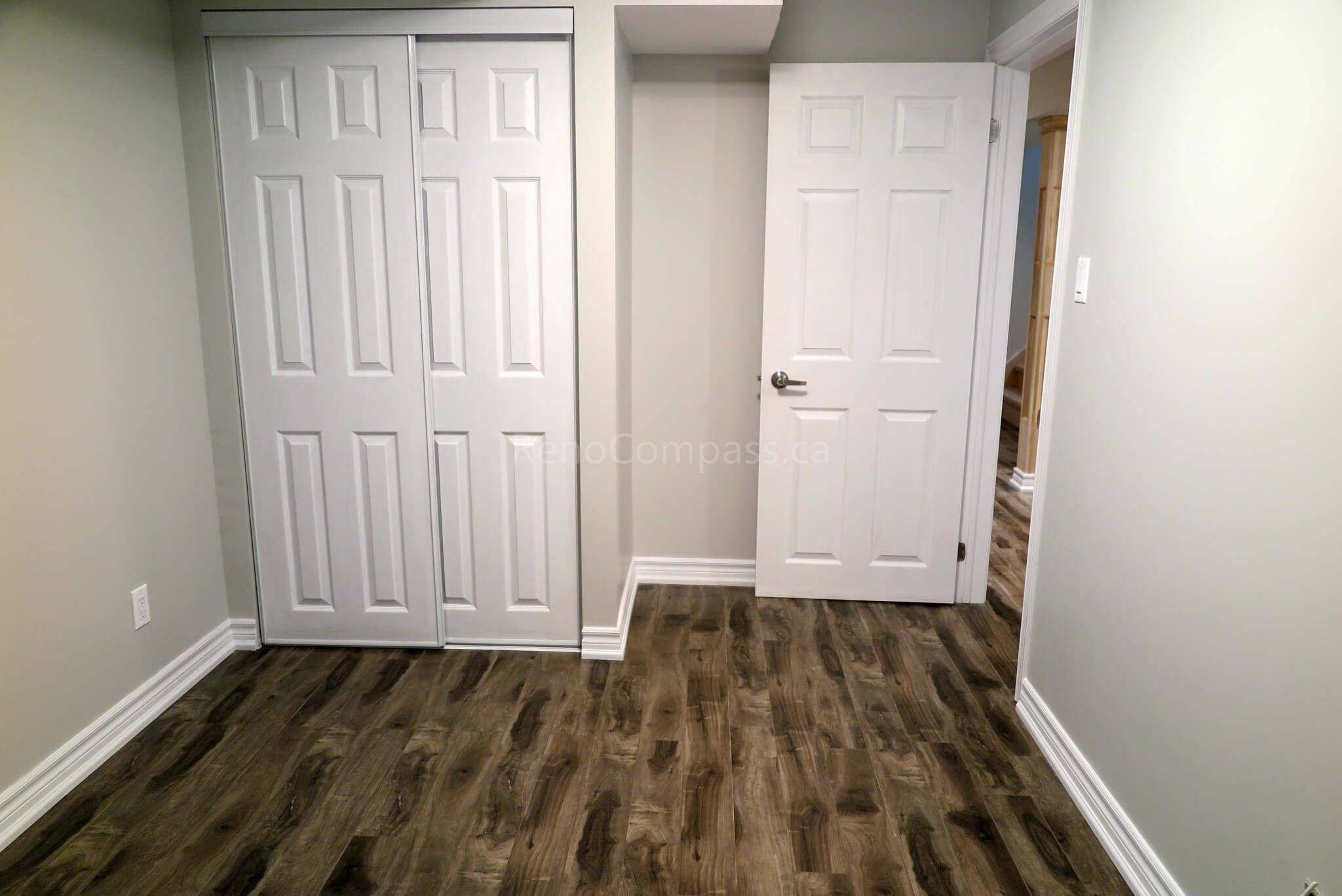 After photo of a completed basement bedroom in Richmond Hill. Featuring modern white double closet doors, freshly painted walls, and luxury vinyl plank flooring — a perfect example of quality basement finishing and smart space design.