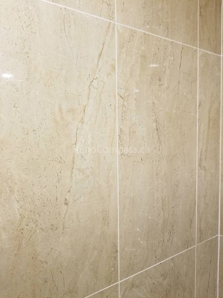 This Vaughan basement bathroom renovation highlights premium beige marble-look wall tile installation, creating a clean, elegant, and moisture-resistant shower environment. The large-format tiles and precise grout lines deliver a seamless modern finish while improving durability and easy maintenance. Professionally completed by Reno Compass Inc., this detailed tile work enhances both the visual appeal and functionality of the upgraded basement bathroom space.
