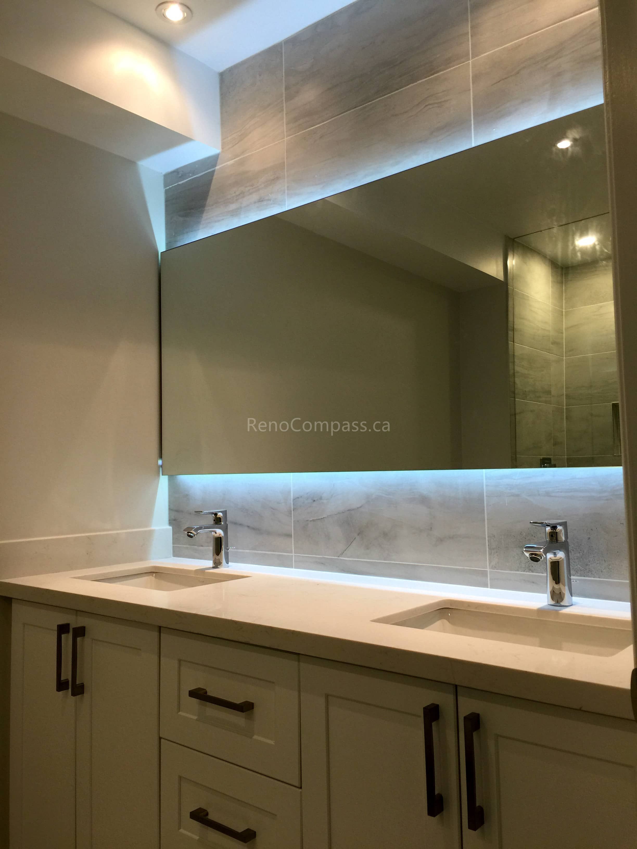 A modern bathroom interior renovation in Toronto featuring a custom double-sink vanity, integrated LED mirror lighting, and sleek contemporary fixtures. The design focuses on functionality, clean detailing, and soft ambient lighting, highlighting professional Toronto interior renovation and interior design craftsmanship.