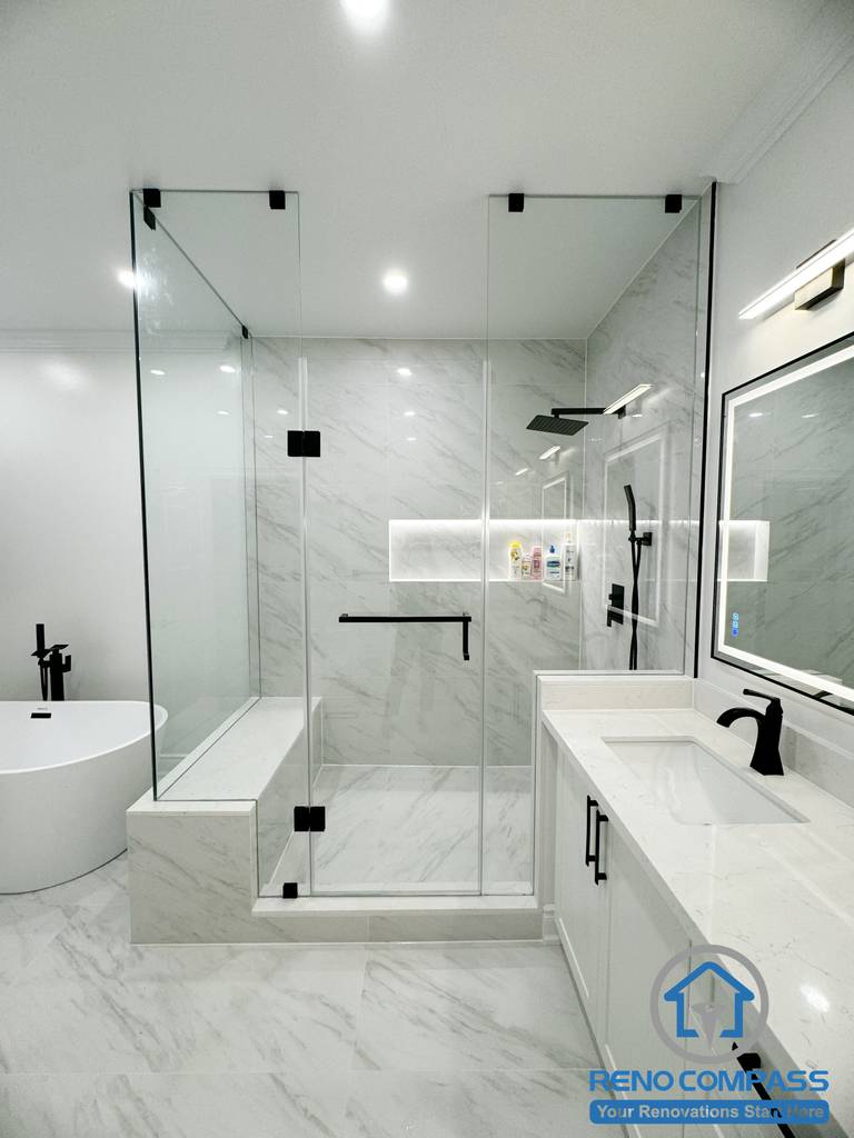 This Vaughan bathroom renovation presents a complete spa-inspired layout featuring a frameless glass shower, freestanding bathtub, and custom double vanity with quartz countertops. Large-format marble-look tiles, matte black fixtures, and integrated lighting create a bright, cohesive, and modern atmosphere. Completed by an experienced Toronto Renovation Company, this bathroom design emphasizes comfort, functionality, and clean contemporary craftsmanship.
