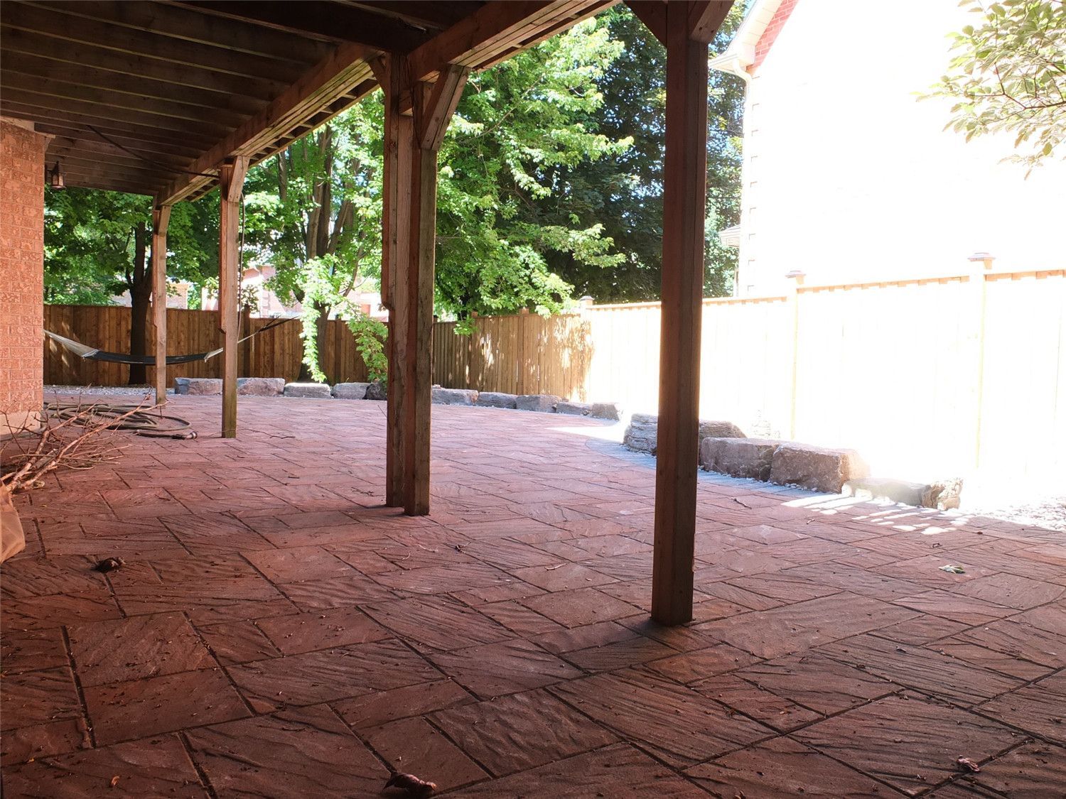 This Aurora backyard renovation features a spacious covered interlocking patio designed for year-round outdoor enjoyment. The stamped concrete-style interlock pattern adds texture and character, while the extended layout maximizes functional living space beneath the wooden deck structure.

Reno Compass Inc. completed this landscaping upgrade with precise leveling and durable paver installation, creating a low-maintenance, weather-resistant surface ideal for gatherings, relaxation, and outdoor entertaining.