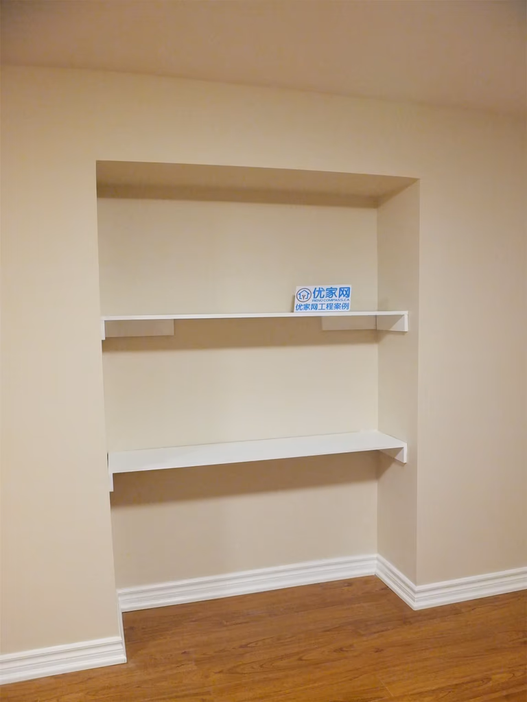 This Markham basement renovation includes a custom built-in wall shelving unit designed to add practical storage and display space. The recessed niche with clean white shelves contrasts beautifully with the warm neutral wall paint and wood-style flooring, creating a functional and visually balanced interior feature. The installation enhances basement organization while maintaining a modern and tidy interior design.